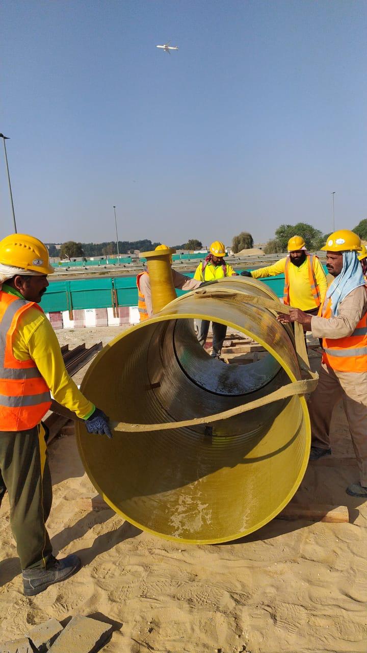Pipeline work area with workers and welded sections near earthmoving equipment