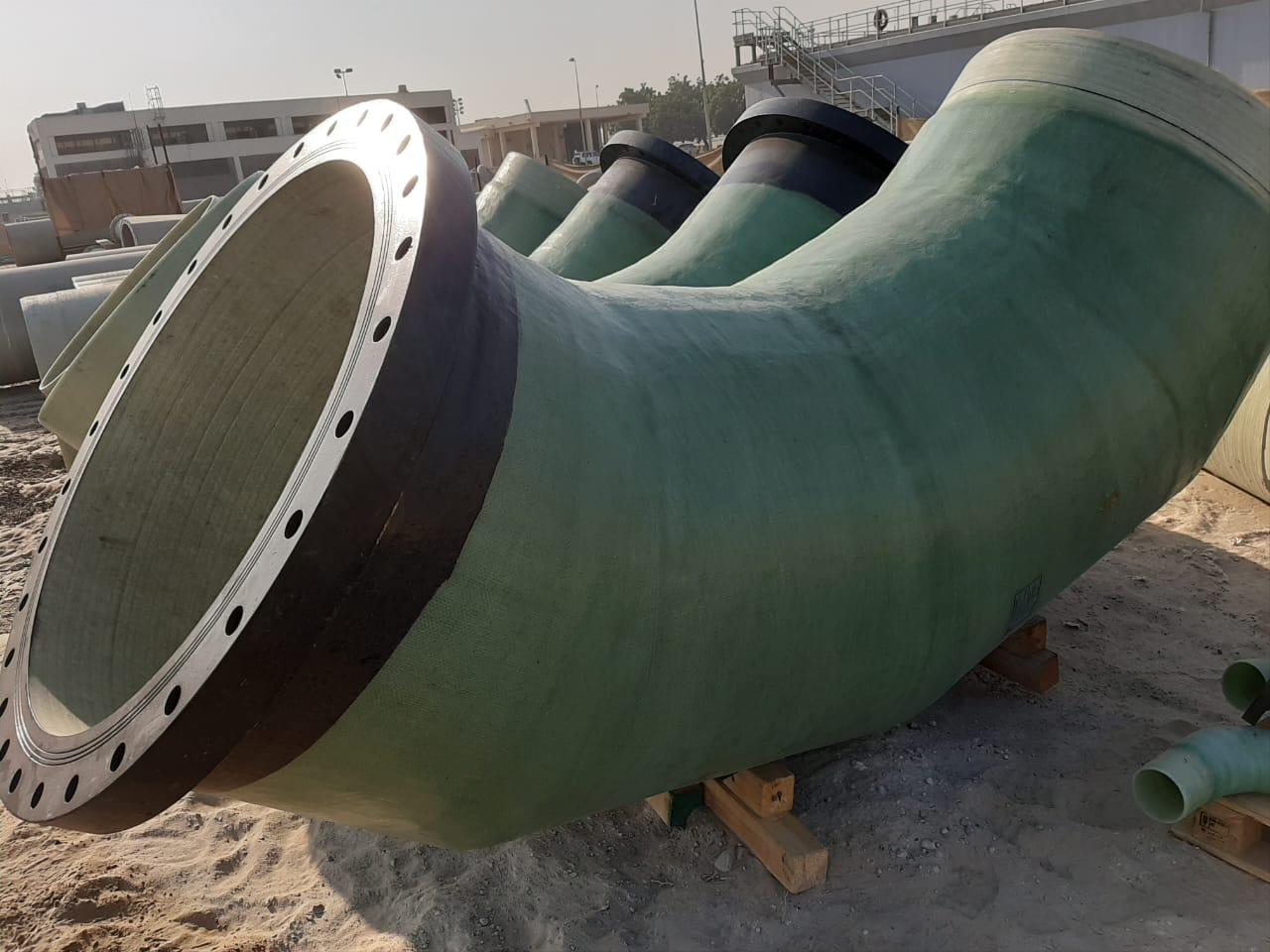 Pipeline construction site with large pipes and temporary supports in a cleared outdoor area