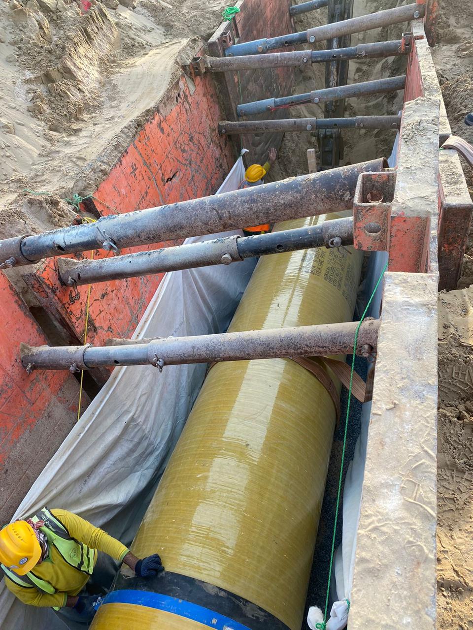 Pipeline trench with large diameter pipes and construction equipment in an outdoor work zone